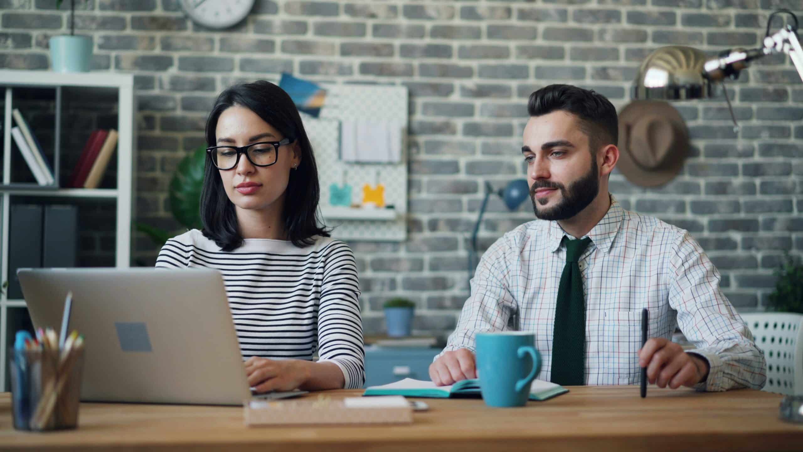 A man and woman looking at a laptop